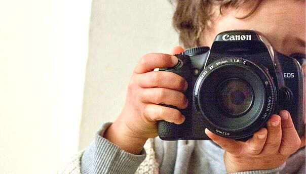 Kind mit analoger Kamera vor dem Gesicht